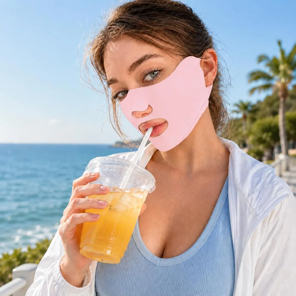 woman drinking through the open mouth of a pink UV face mask