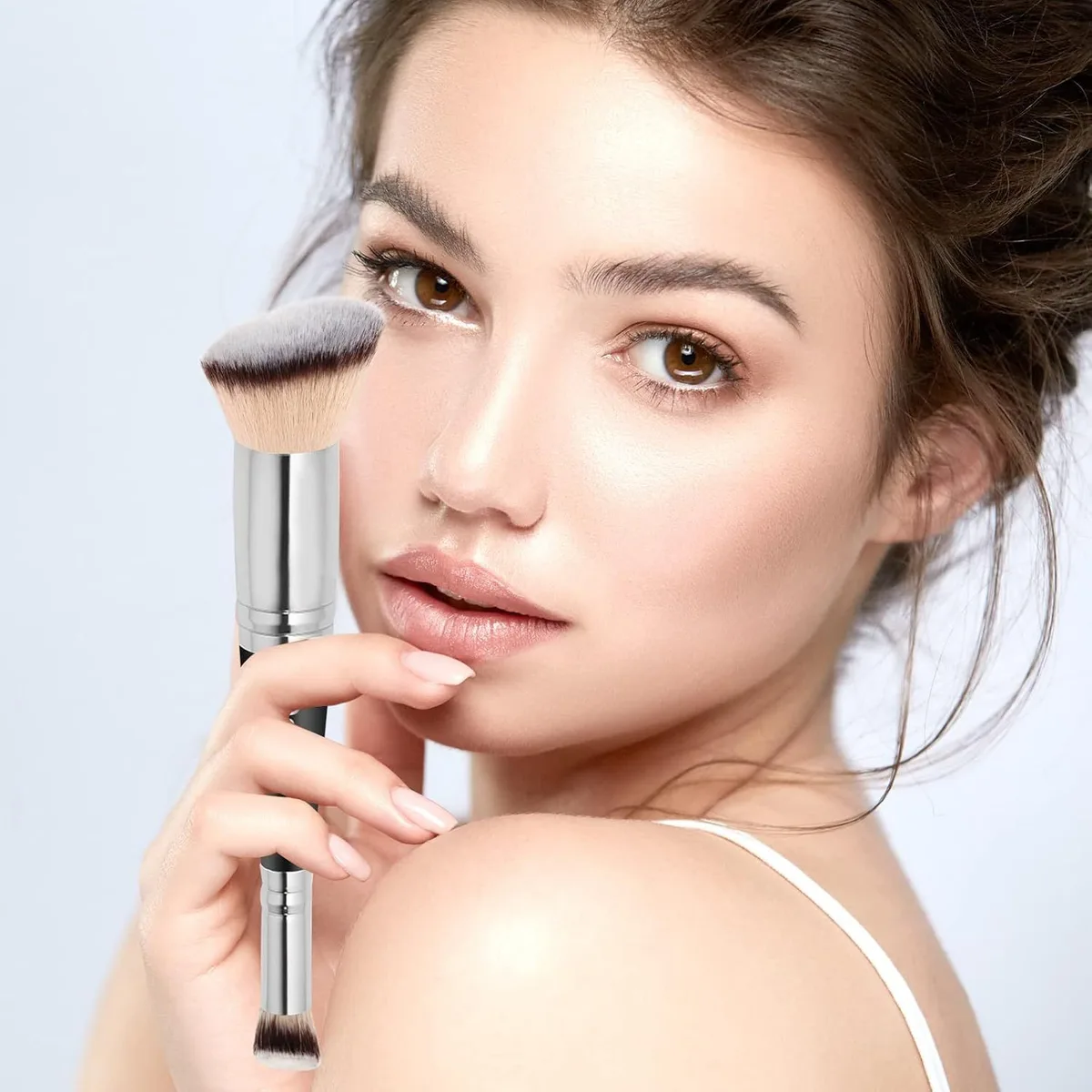 woman holding a dual-ended foundation and concealer brush to her face